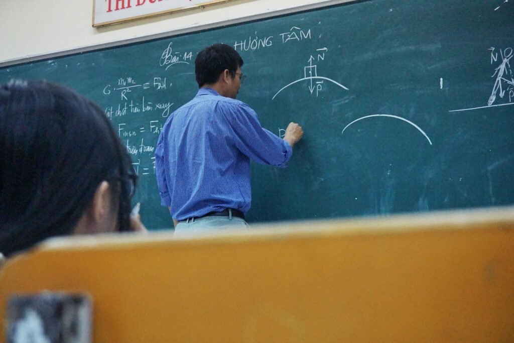Profesor scriind la tablă în fața elevilor